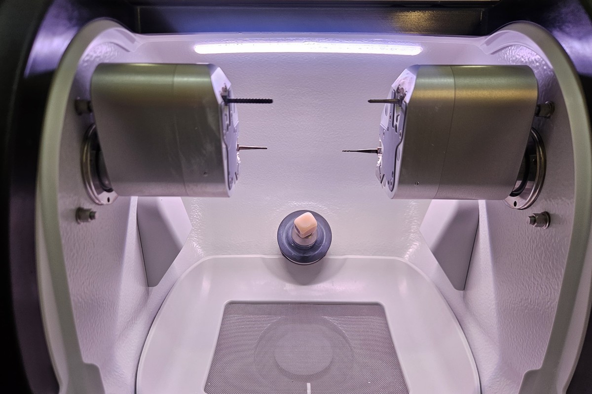 A ceramic block being milled inside the CEREC Primemill at Calm Dental, the two grinding spindles either side of the block