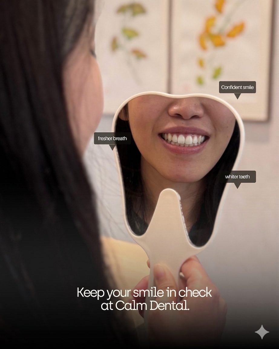 A patient checking her teeth in a hand mirror at Calm Dental