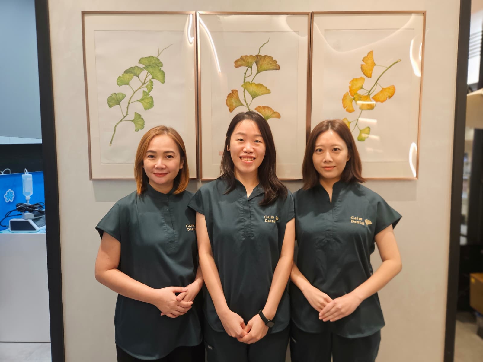 Three of the Calm Dental support team at the clinic, in front of the ginkgo triptych
